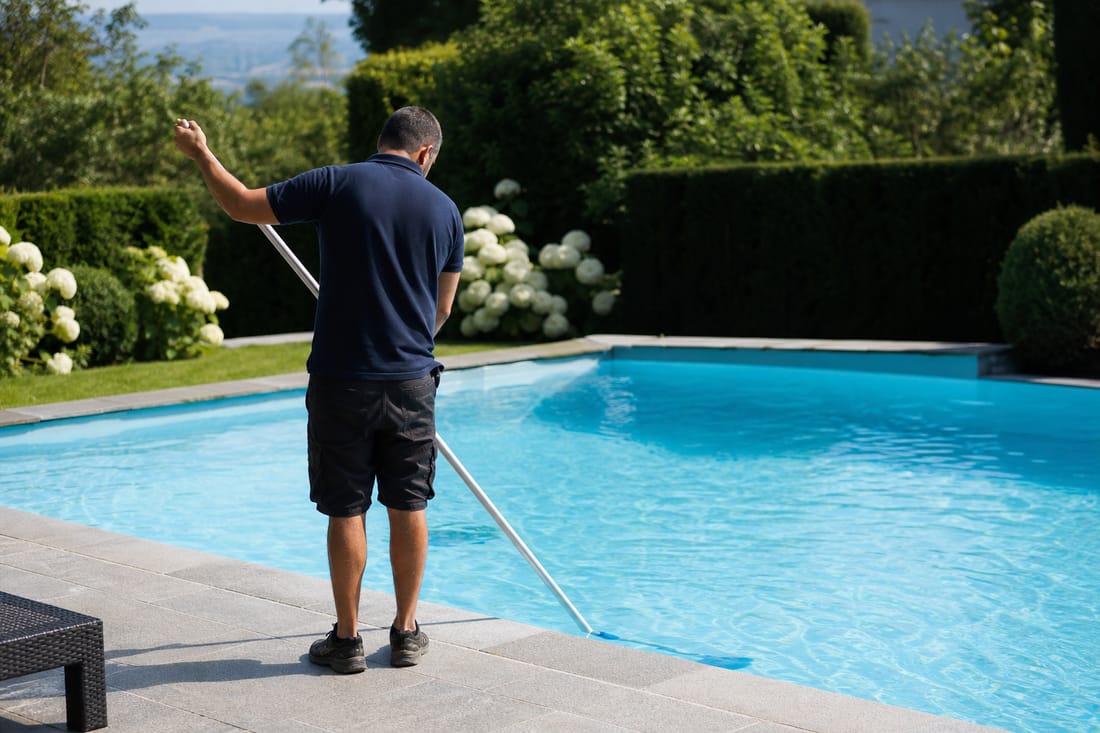 Beispiel: Techniker von hinten bei der Poolpflege mit Bürste